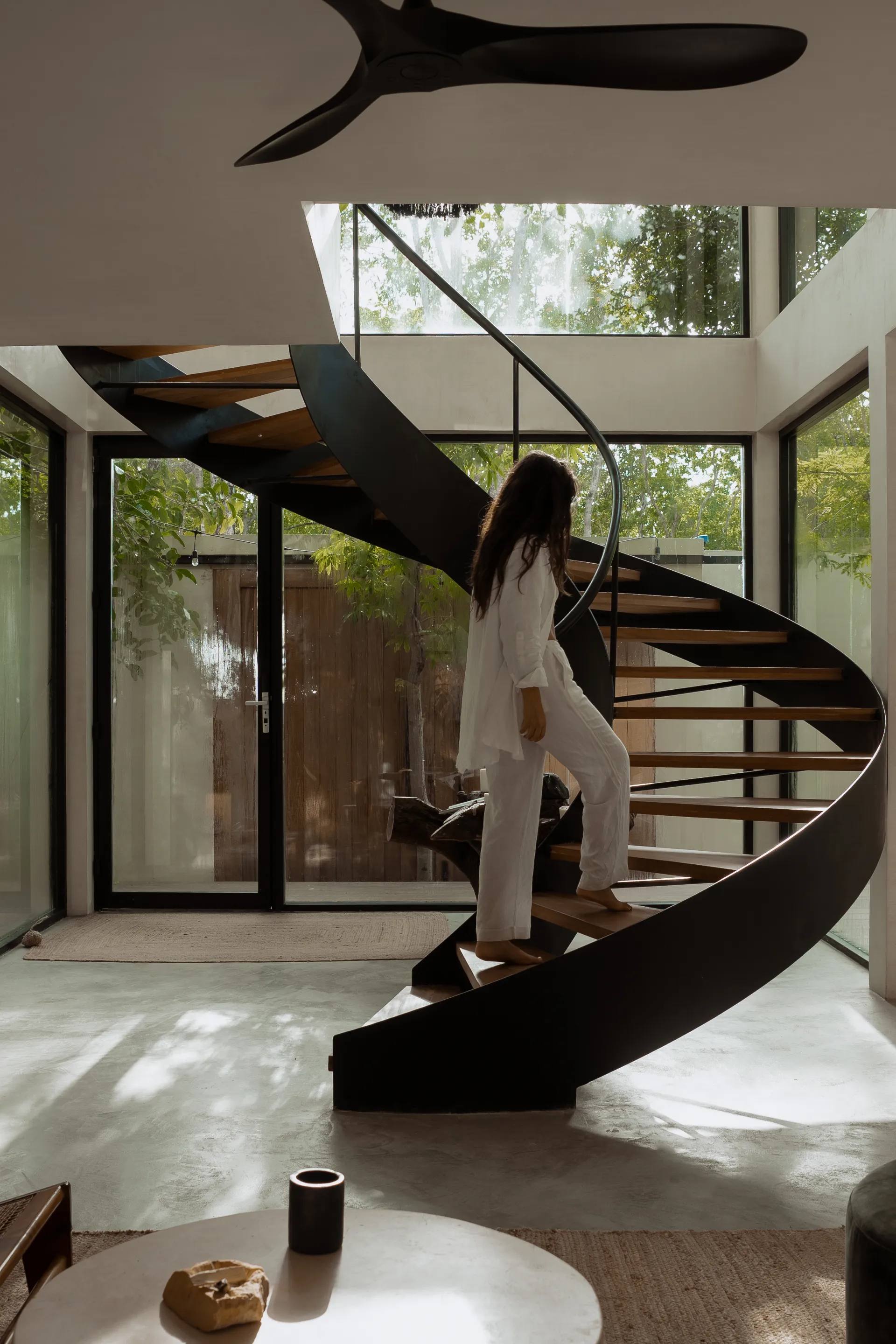 Woman ascending sculptural spiral staircase at Casa Nati with jungle views