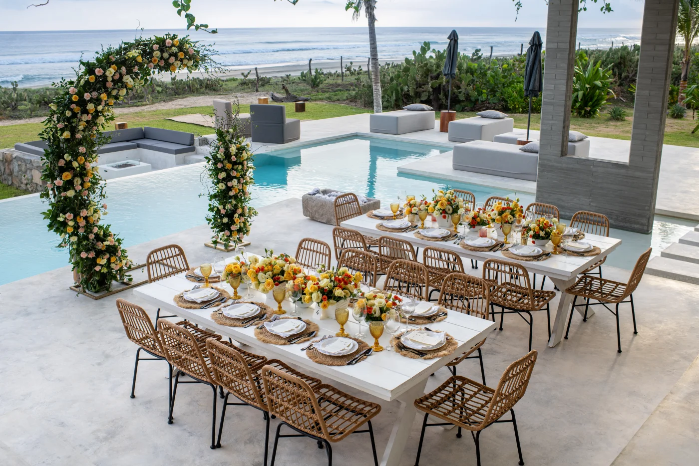 Elegant poolside dinner setup with floral arch and ocean views