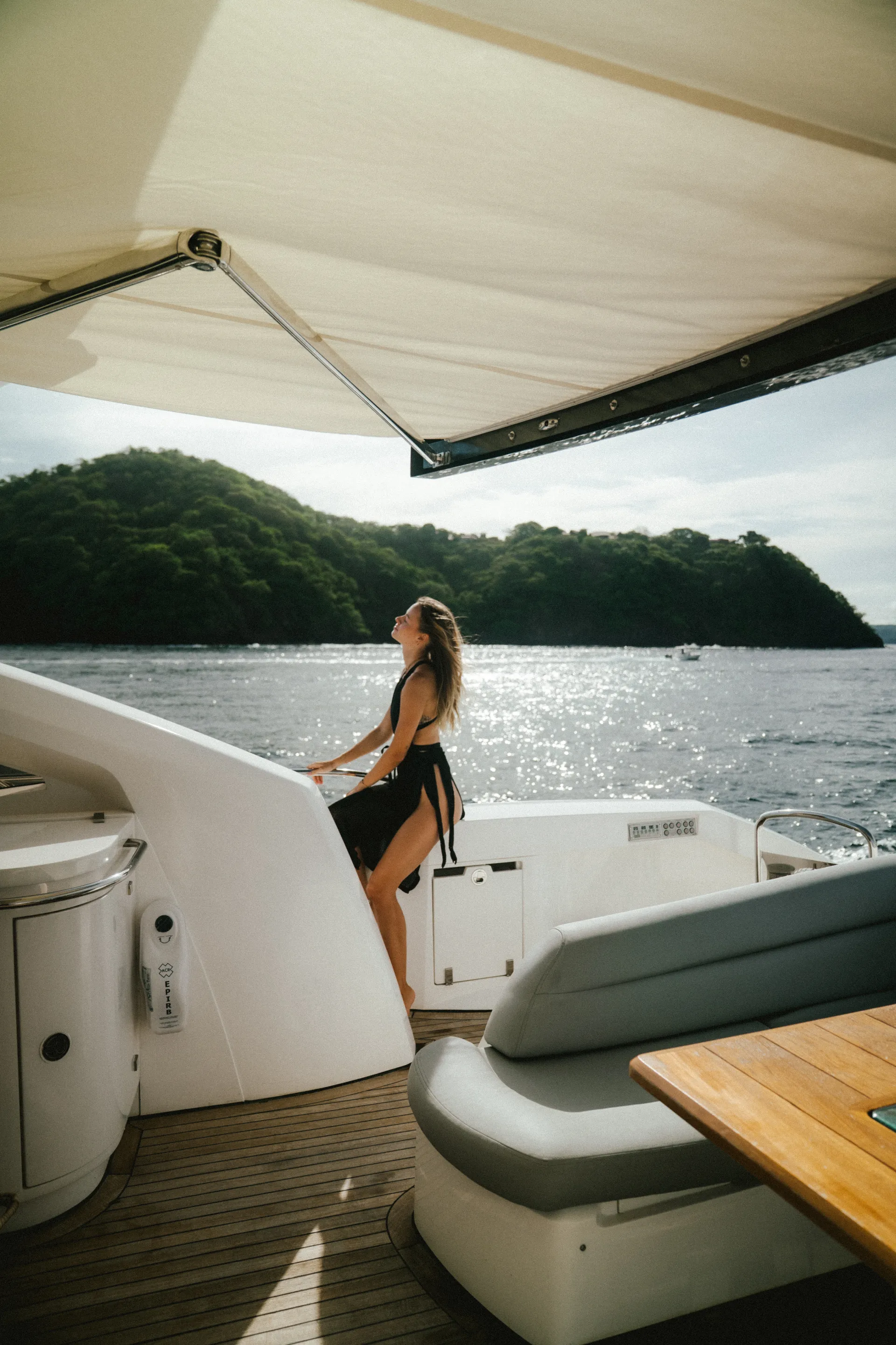 Woman on yacht deck gazing at jungle-covered Costa Rican coastline