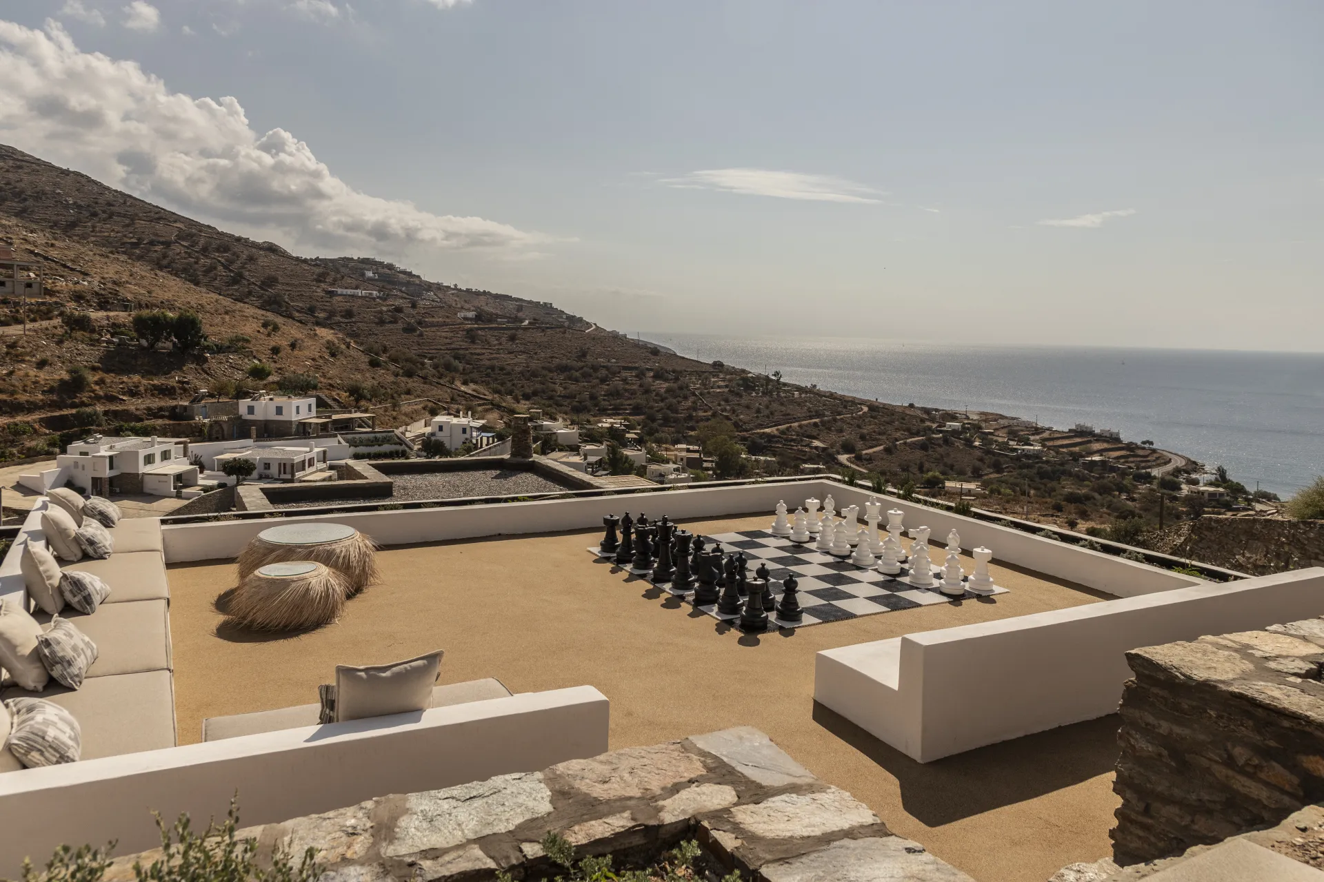 Outdoor terrace with giant chess set and panoramic Aegean views at Villa Naos