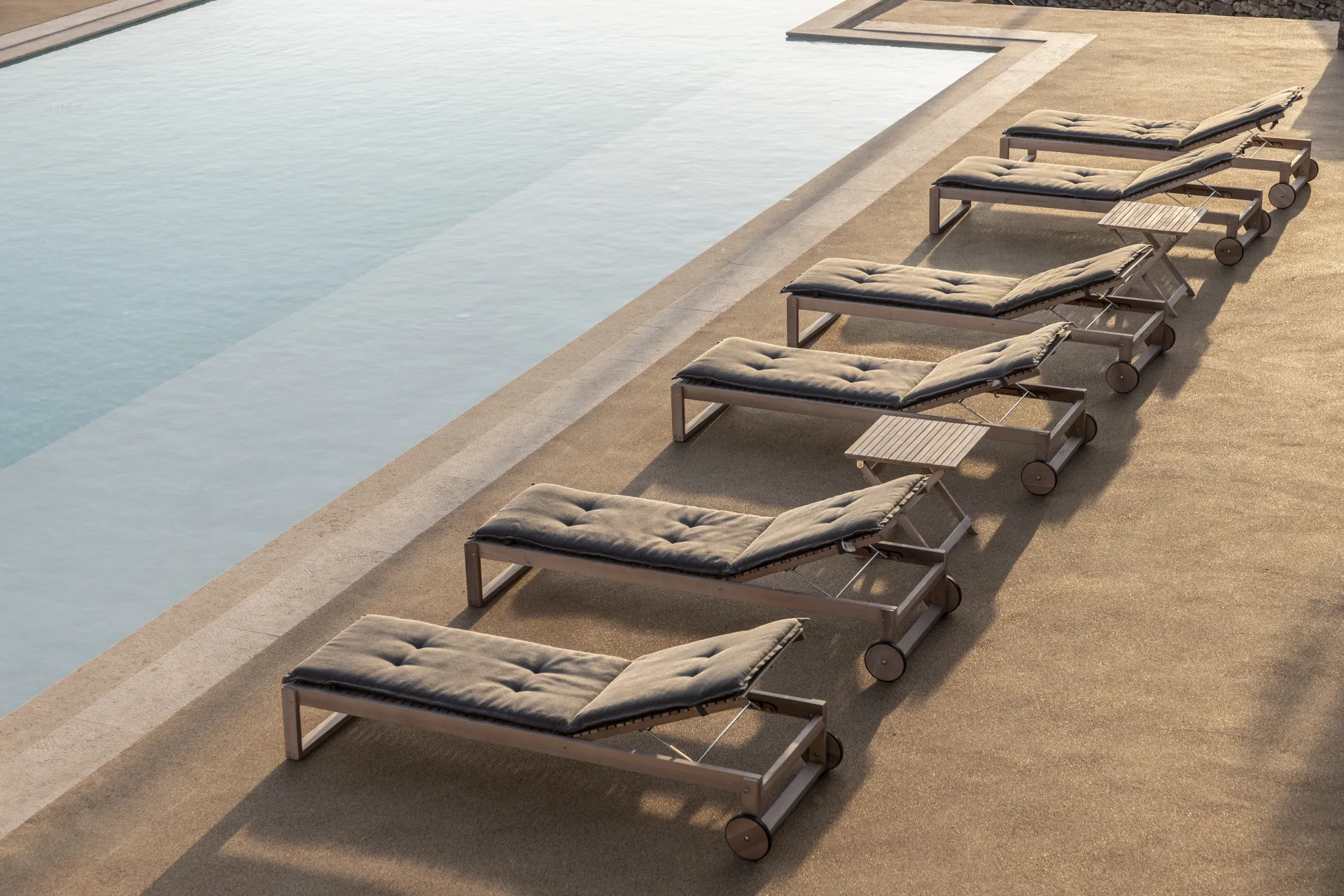 Row of sun loungers beside infinity pool at Villa Naos