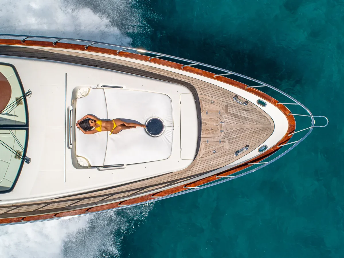 Aerial of a guest sunbathing on the bow of the Azimut 84 over turquoise water, a World Cup off-day charter from Miami