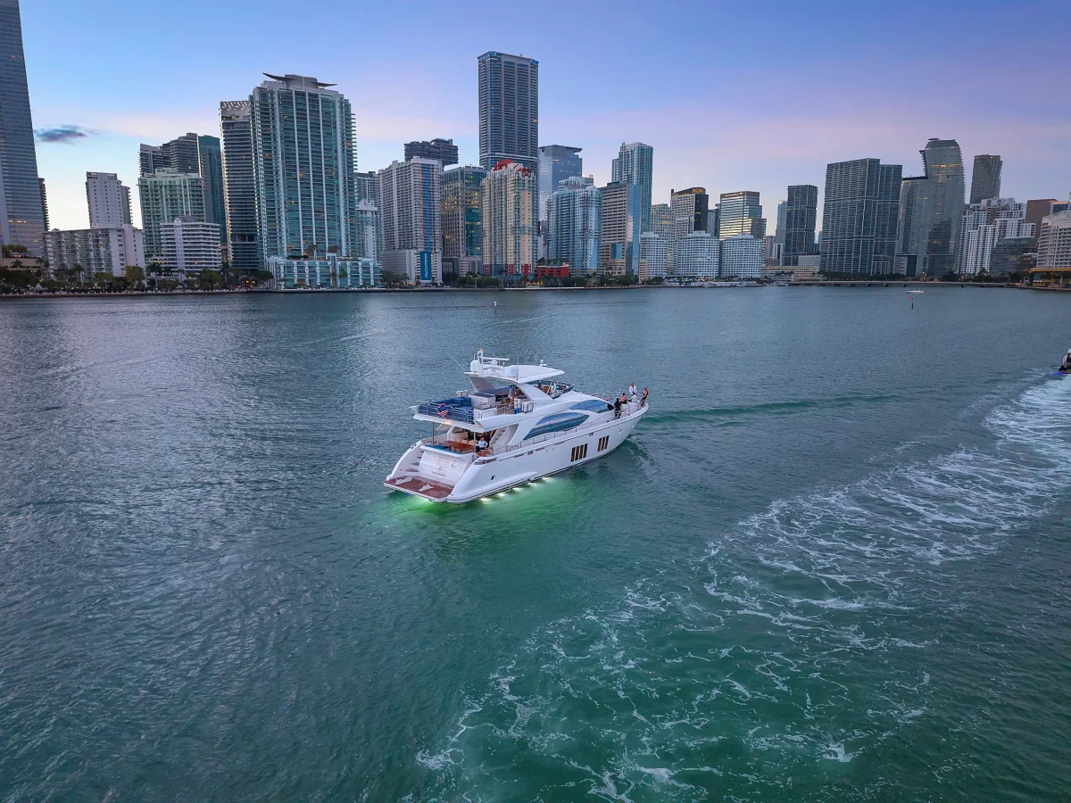 Azimut 88 cruising Biscayne Bay at dusk with Miami skyline and green LED hull lights