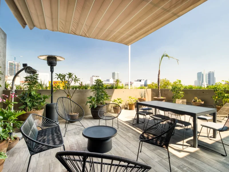 Rooftop terrace in Condesa, Mexico City, seating and a long dining table under an awning with the skyline behind