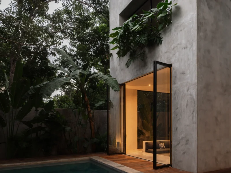 Private chef preparing dinner on a villa outdoor kitchen with lit terrace and pool behind