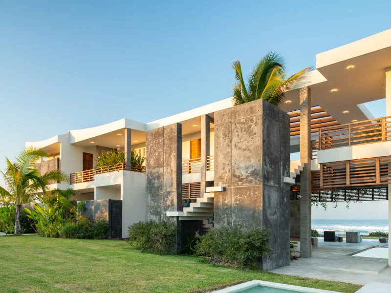 Oceanfront villa at dusk, palms and pool terrace above the surf