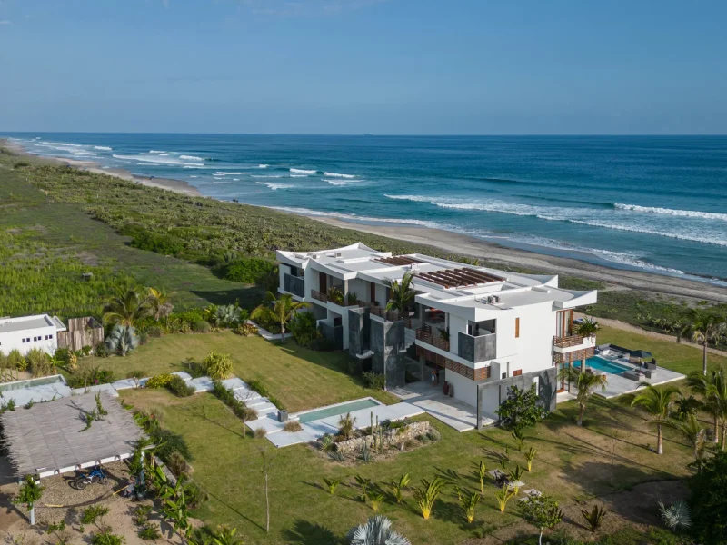 Aerial view of an oceanfront villa, its pools and the breaking surf below