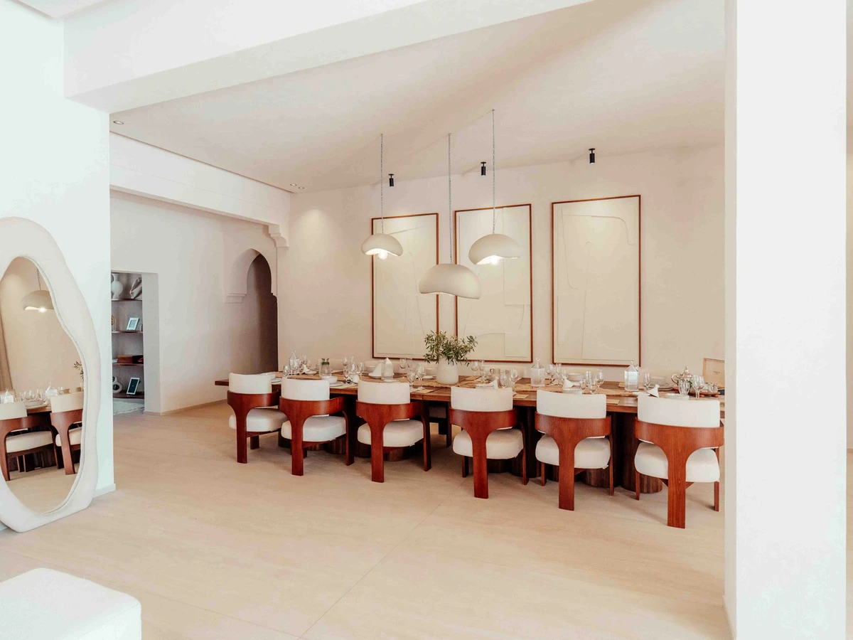 The dining hall at Palais Eliah near Marrakech, one long table with its chairs under a row of framed panels