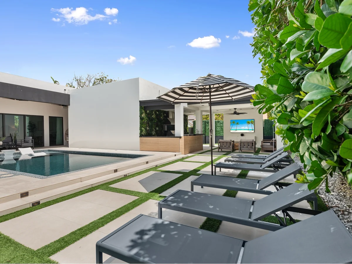 Long indoor-outdoor dining table opening to the pool deck at Villa Grace, a value group base for a World Cup party of 14