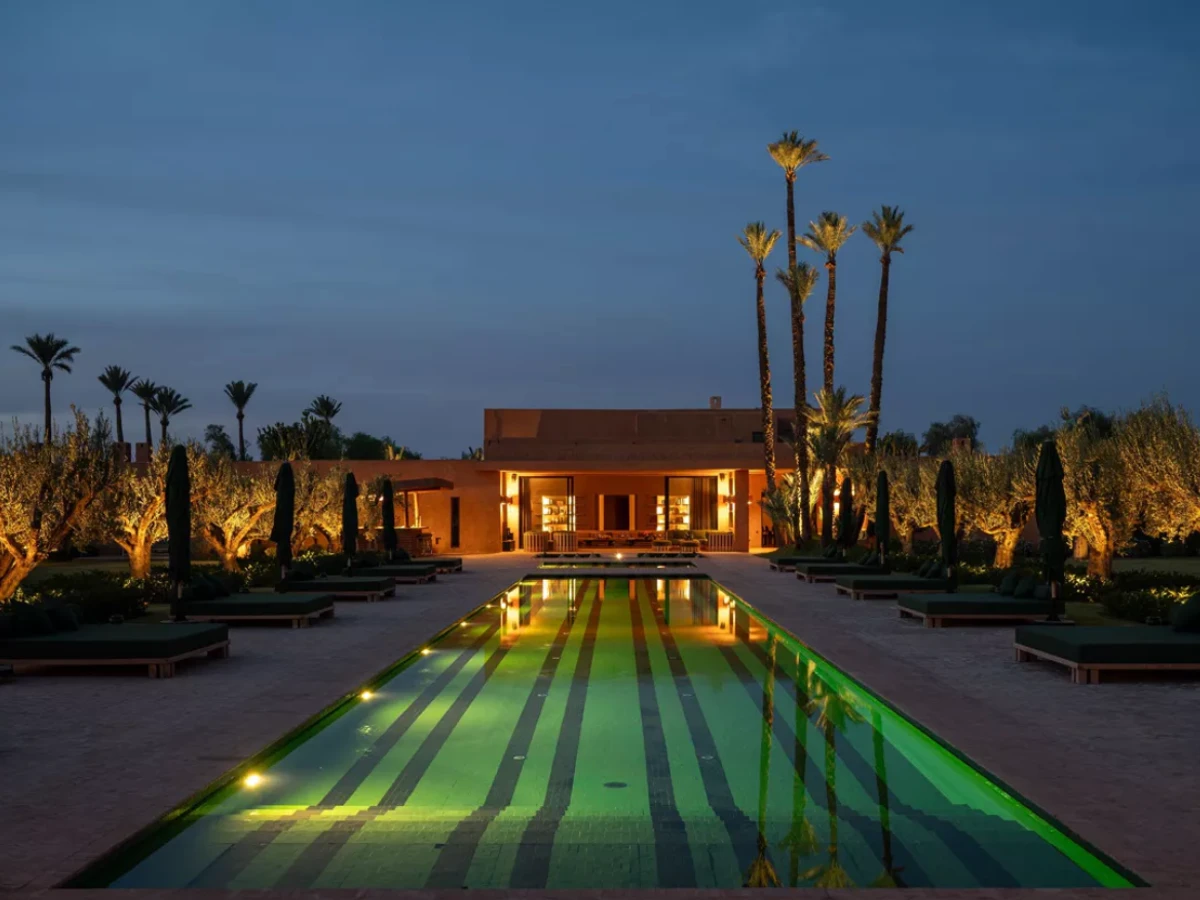 Villa Kemgia near Marrakech at dusk: a long lit pool between loungers, lined with palms, leading to the main house