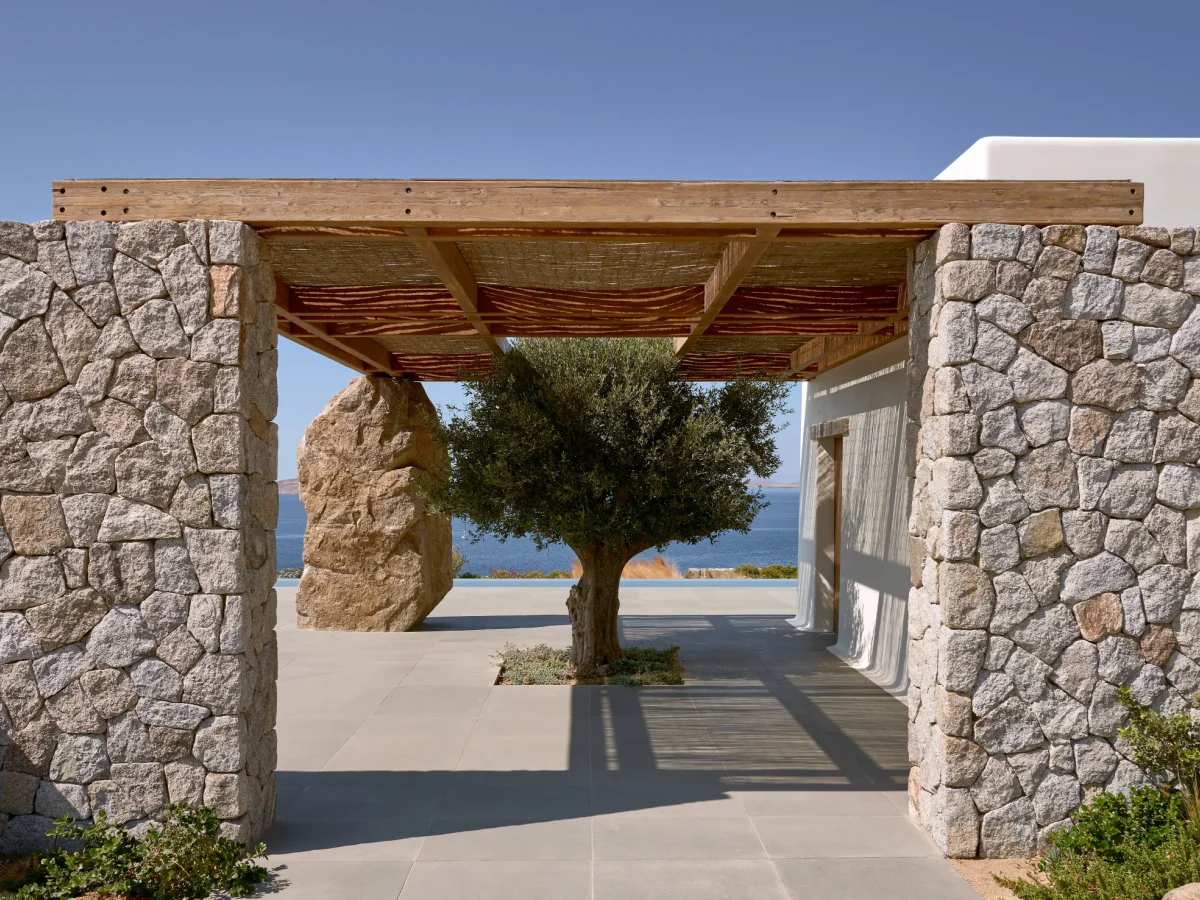Shaded outdoor dining terrace at a Mykonos villa set for a large group in the late afternoon