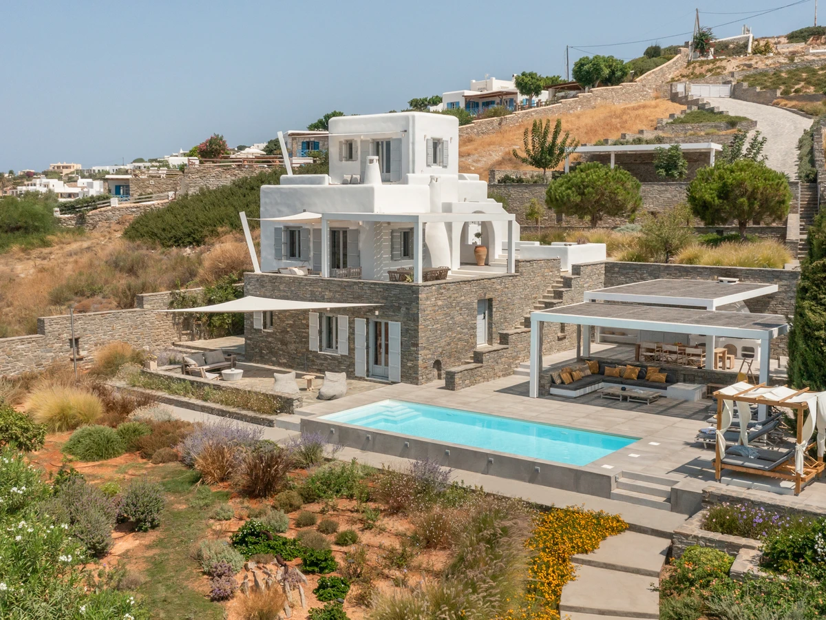 Cycladic villa exterior with pool and shaded terrace above the Aegean on Paros