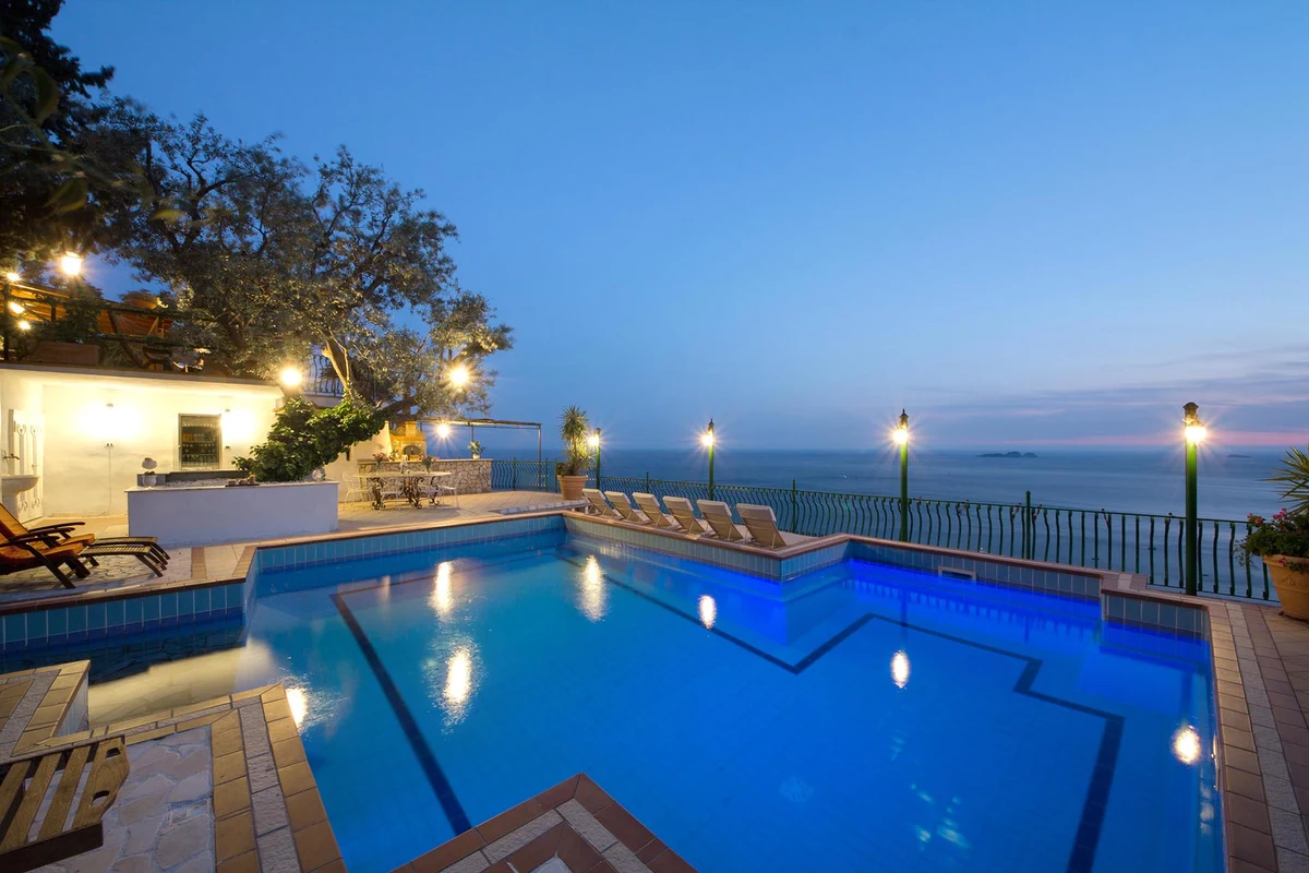 Pool terrace with loungers and partial shade above the Amalfi coastline
