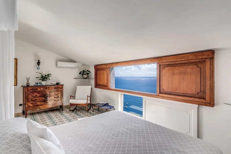 Positano bay from a clifftop villa terrace at golden hour with pastel houses cascading down