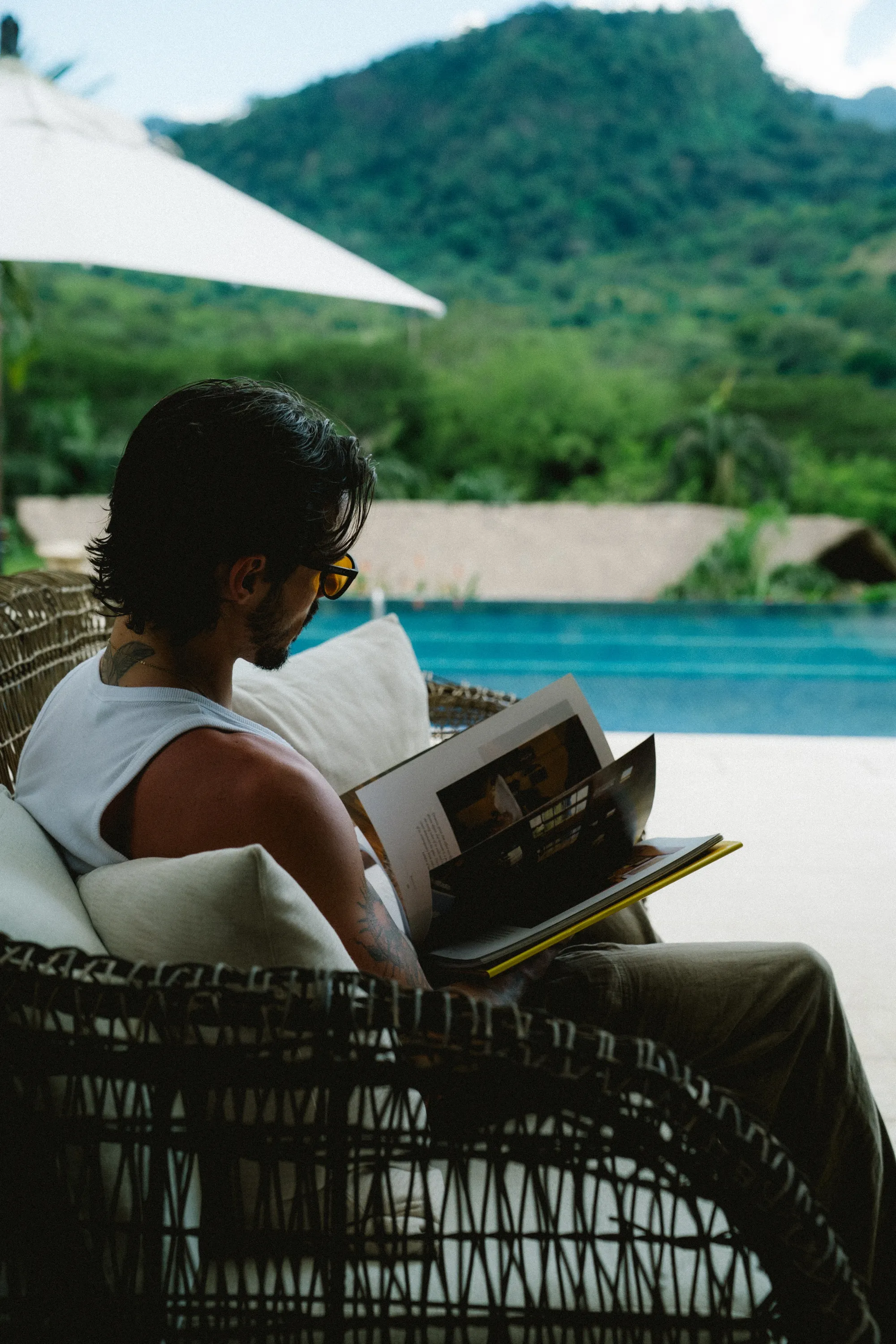 Person relaxing by infinity pool overlooking green mountains
